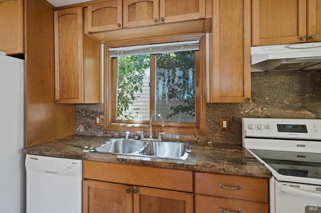 kitchen with a sink, backsplash, white appliances, brown cabinets, and under cabinet range hood