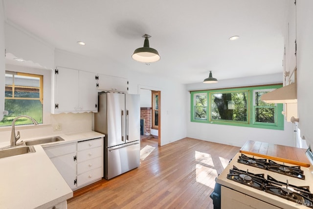 kitchen featuring white cabinets, sink, backsplash, hanging light fixtures, and stainless steel refrigerator