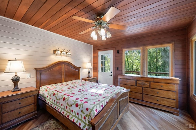 bedroom featuring wood ceiling, ceiling fan, light hardwood / wood-style flooring, and wooden walls