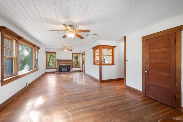 unfurnished living room with ceiling fan, a brick fireplace, dark hardwood / wood-style floors, and wooden ceiling