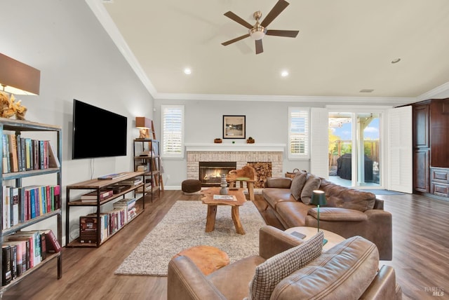 living room with crown molding, a brick fireplace, a healthy amount of sunlight, and light wood-type flooring