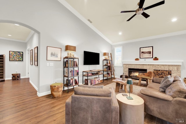 living room with hardwood / wood-style floors, a fireplace, ornamental molding, and vaulted ceiling