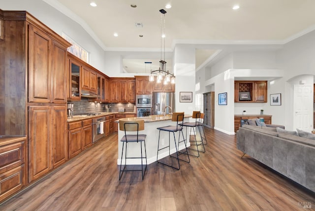 kitchen featuring pendant lighting, a breakfast bar, stainless steel appliances, light stone counters, and an island with sink