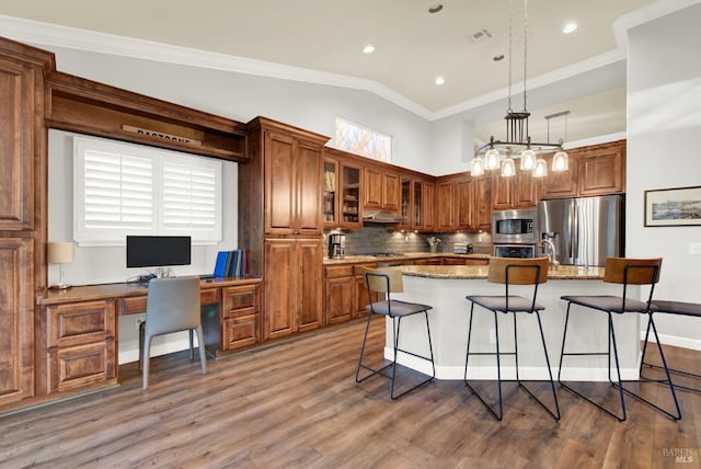 kitchen featuring appliances with stainless steel finishes, pendant lighting, tasteful backsplash, a kitchen island with sink, and light stone counters