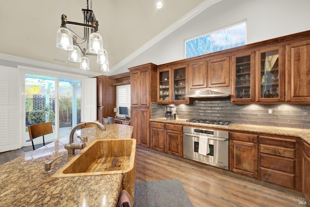 kitchen featuring lofted ceiling, sink, decorative backsplash, stainless steel appliances, and light stone countertops