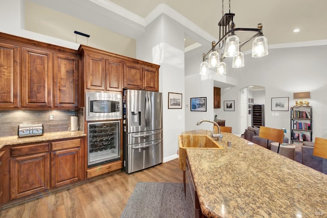 kitchen with sink, pendant lighting, stainless steel appliances, light stone countertops, and backsplash