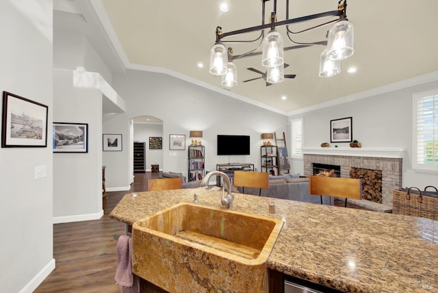 kitchen featuring sink, ceiling fan, hanging light fixtures, ornamental molding, and a brick fireplace