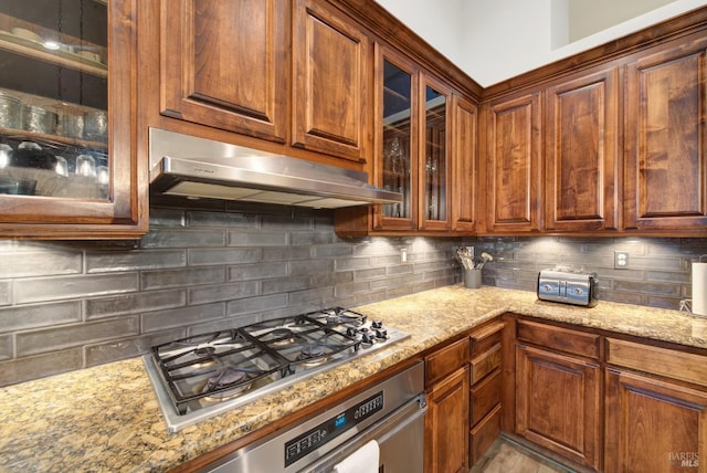 kitchen featuring light stone counters, decorative backsplash, and stainless steel appliances