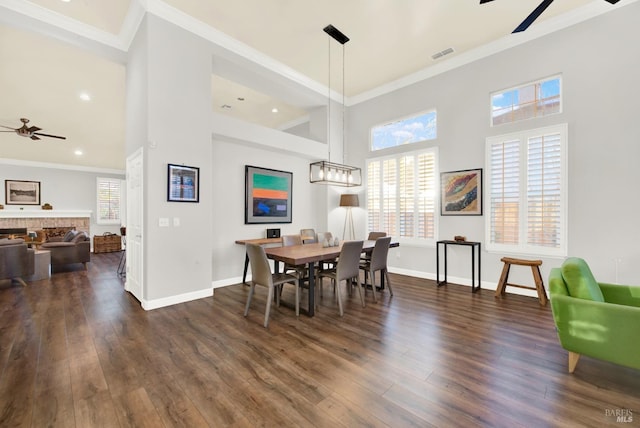 dining space with dark hardwood / wood-style flooring, a brick fireplace, ornamental molding, and ceiling fan