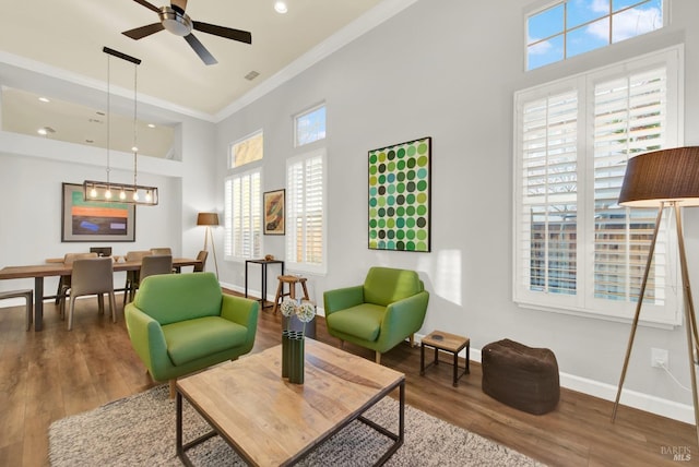 living area with crown molding, ceiling fan, a high ceiling, and hardwood / wood-style flooring