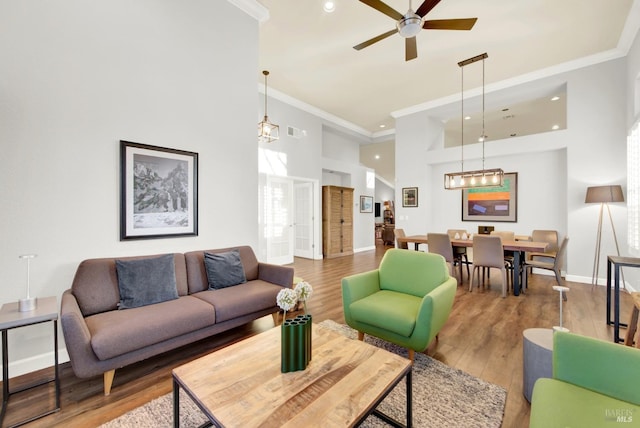 living room featuring wood-type flooring, ornamental molding, and ceiling fan