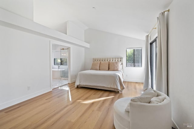 bedroom featuring ensuite bath, vaulted ceiling, and light wood-type flooring