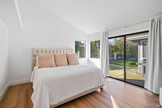 bedroom featuring high vaulted ceiling, hardwood / wood-style floors, multiple windows, and access to outside