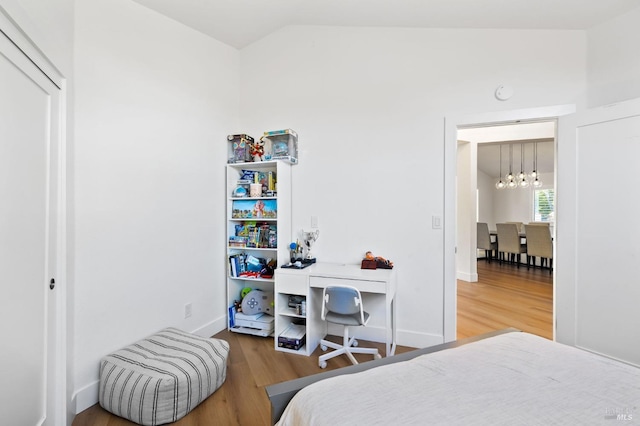 bedroom with vaulted ceiling, a chandelier, and hardwood / wood-style floors