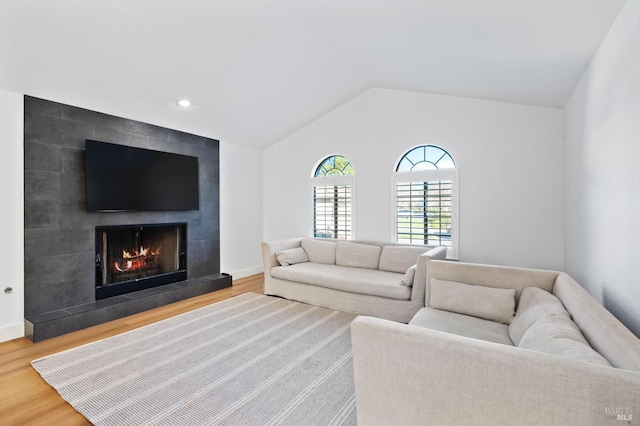 living room featuring a tile fireplace, lofted ceiling, and hardwood / wood-style floors