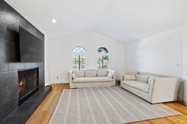 living room with lofted ceiling, hardwood / wood-style flooring, and a large fireplace