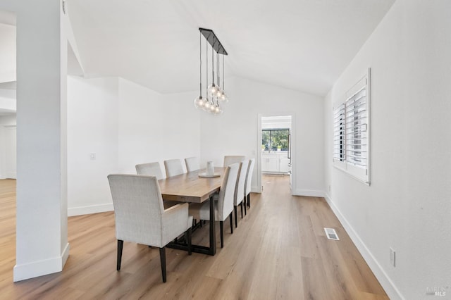 dining space featuring vaulted ceiling, a notable chandelier, and light hardwood / wood-style floors