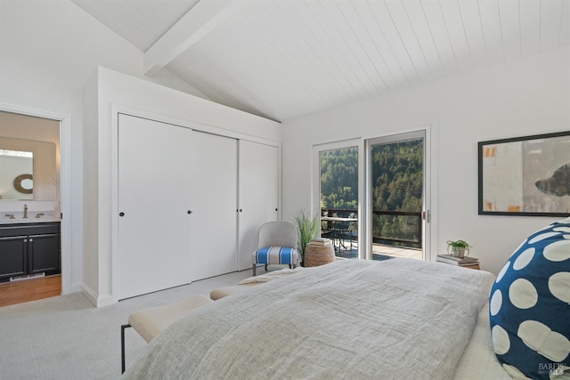 bedroom featuring ensuite bath, light carpet, a closet, access to outside, and lofted ceiling with beams