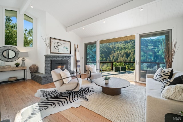 living room featuring a brick fireplace, light hardwood / wood-style flooring, and lofted ceiling with beams