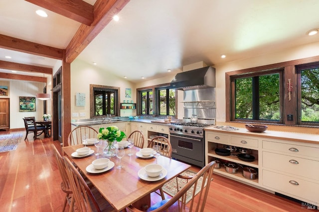 dining area featuring light hardwood / wood-style flooring and lofted ceiling with beams