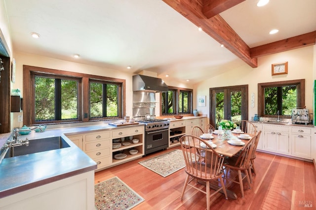 kitchen featuring white cabinets, sink, stainless steel stove, ventilation hood, and light hardwood / wood-style flooring