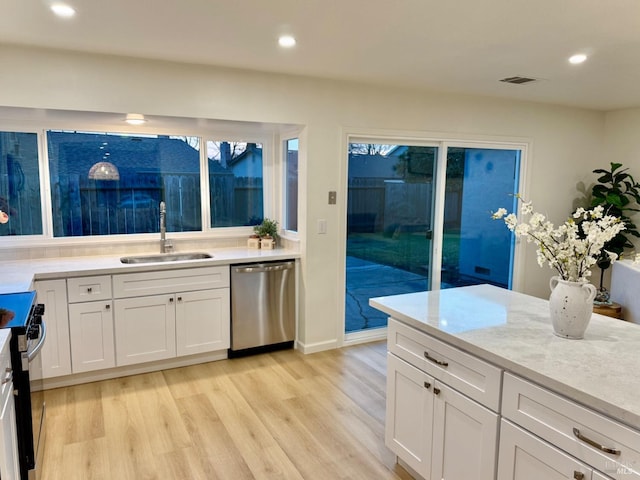 kitchen featuring white cabinetry, sink, light wood-type flooring, and appliances with stainless steel finishes