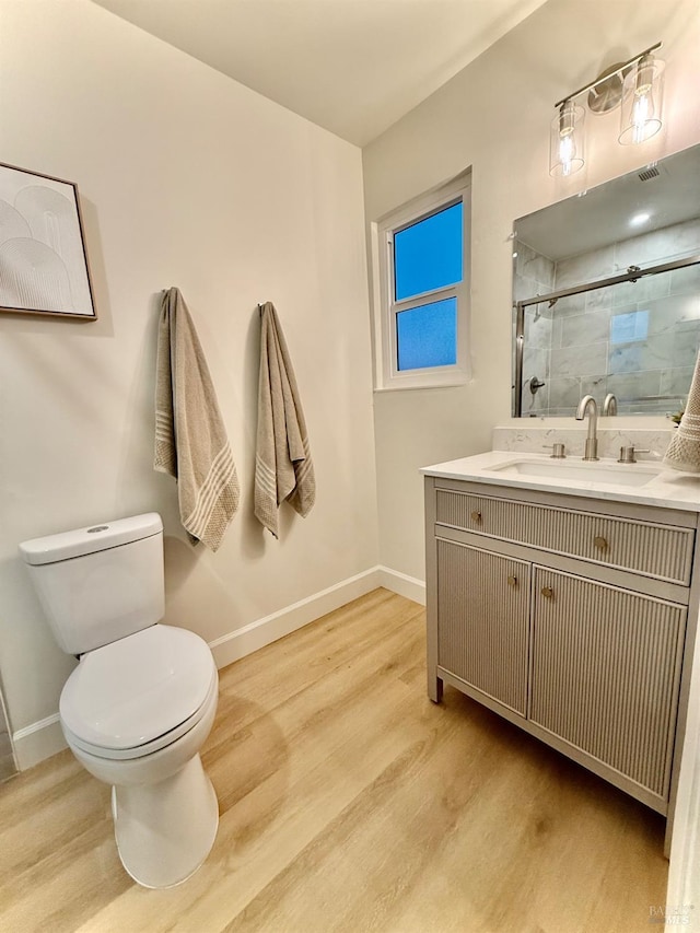 bathroom featuring walk in shower, wood-type flooring, toilet, and vanity