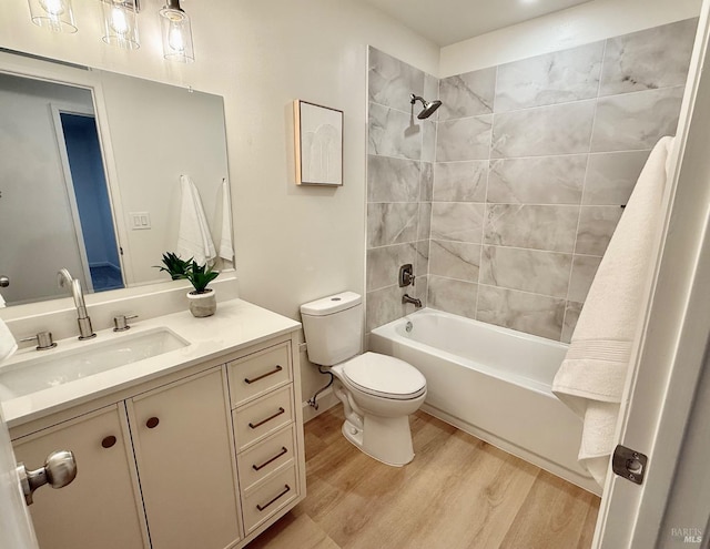 full bathroom featuring wood-type flooring, toilet, tiled shower / bath combo, and vanity