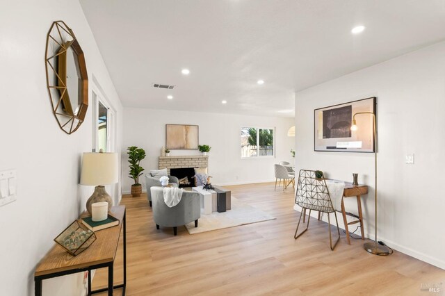 living room featuring a brick fireplace and light hardwood / wood-style flooring