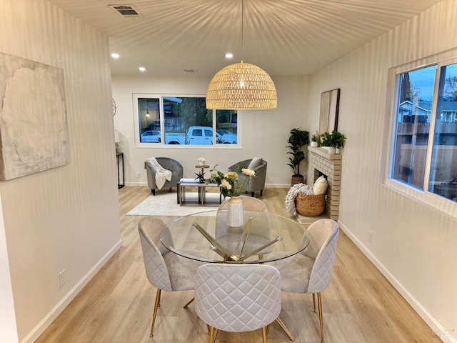 dining space featuring a brick fireplace and light wood-type flooring