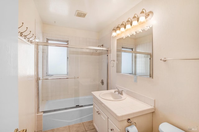 full bathroom featuring vanity, toilet, combined bath / shower with glass door, and tile patterned floors