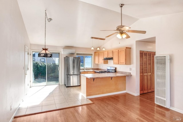 kitchen with kitchen peninsula, light brown cabinets, light wood-type flooring, a kitchen bar, and stainless steel appliances