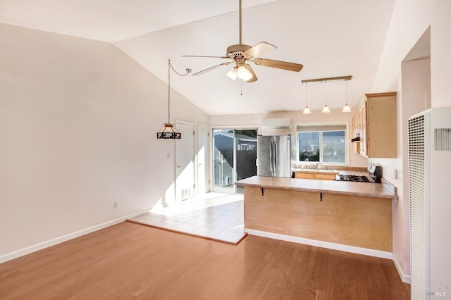 kitchen featuring kitchen peninsula, pendant lighting, stainless steel fridge, stove, and light hardwood / wood-style floors