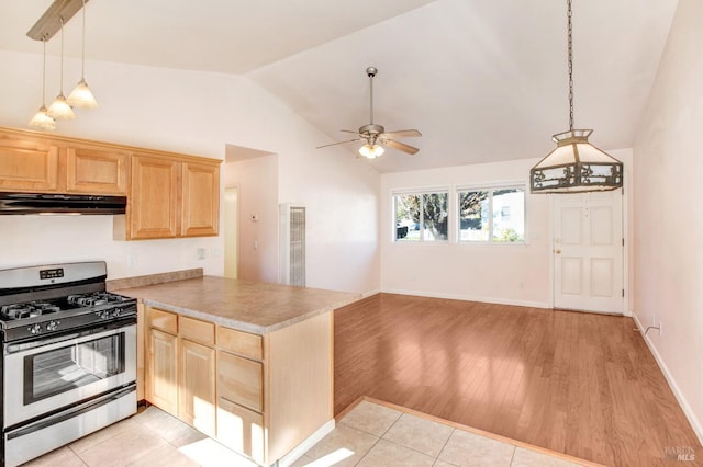 kitchen with kitchen peninsula, pendant lighting, vaulted ceiling, light tile patterned floors, and stainless steel gas range oven