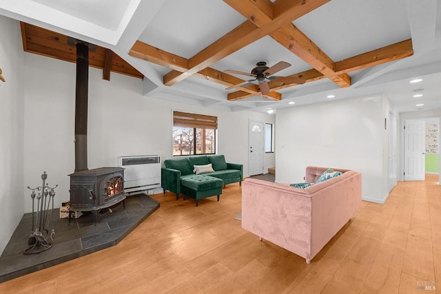 living room featuring a wood stove, light wood-style flooring, and coffered ceiling