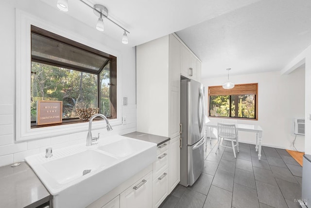 kitchen with white cabinetry, sink, decorative light fixtures, and stainless steel fridge