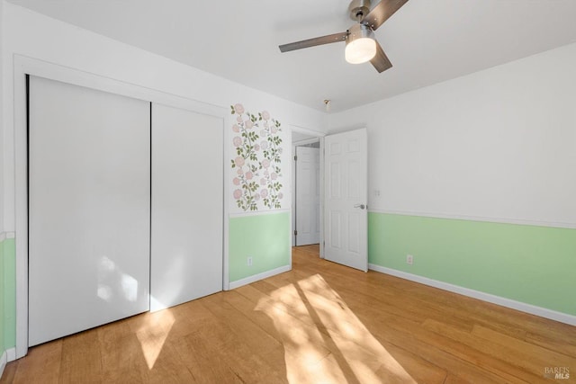 unfurnished bedroom featuring hardwood / wood-style flooring, ceiling fan, and a closet