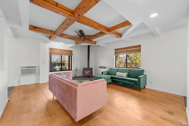 living room with coffered ceiling, a wall mounted air conditioner, light hardwood / wood-style floors, and a wood stove