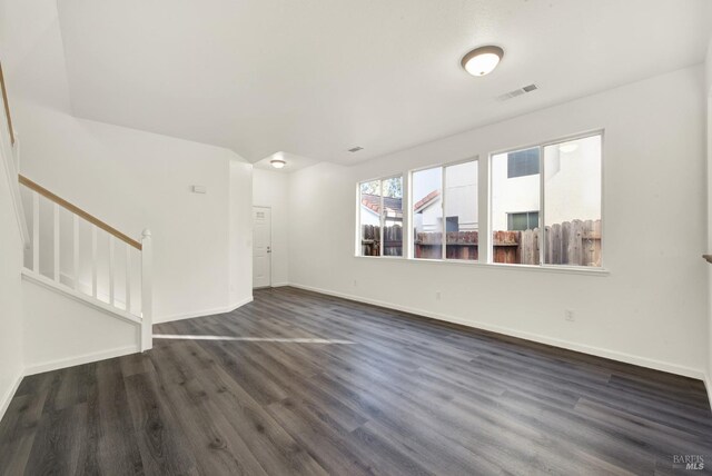 unfurnished living room with visible vents, baseboards, and dark wood finished floors