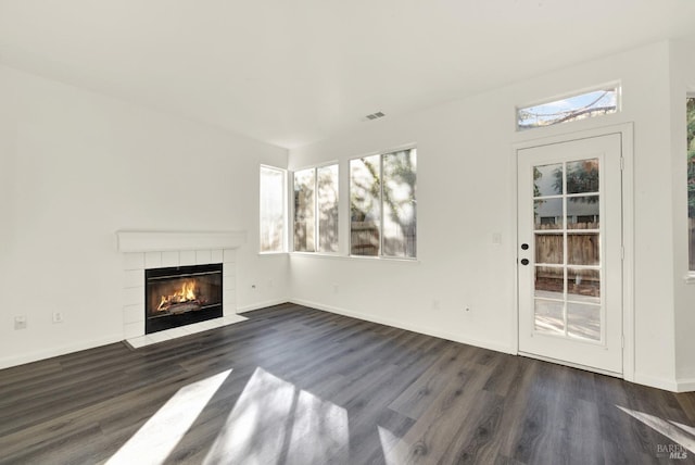 unfurnished living room featuring a tile fireplace, dark wood-style flooring, baseboards, and visible vents