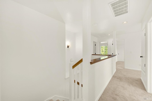 corridor featuring visible vents, baseboards, an upstairs landing, and light colored carpet