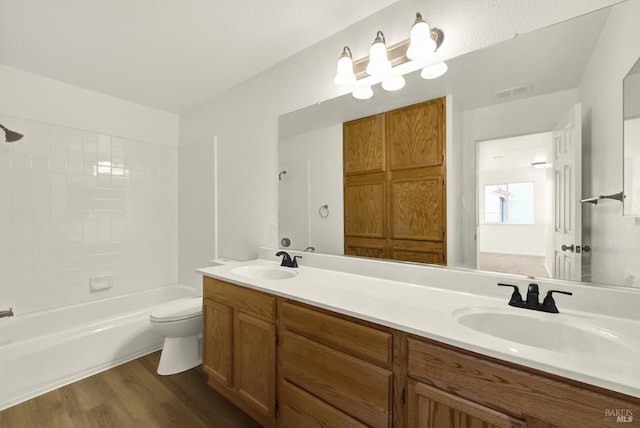full bathroom featuring toilet, shower / bath combination, wood finished floors, and a sink
