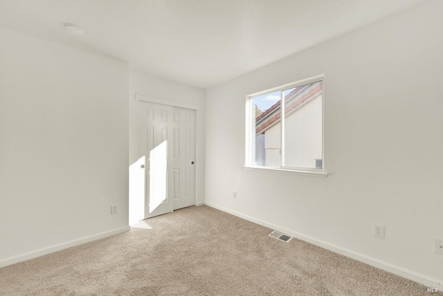 carpeted spare room featuring baseboards and visible vents