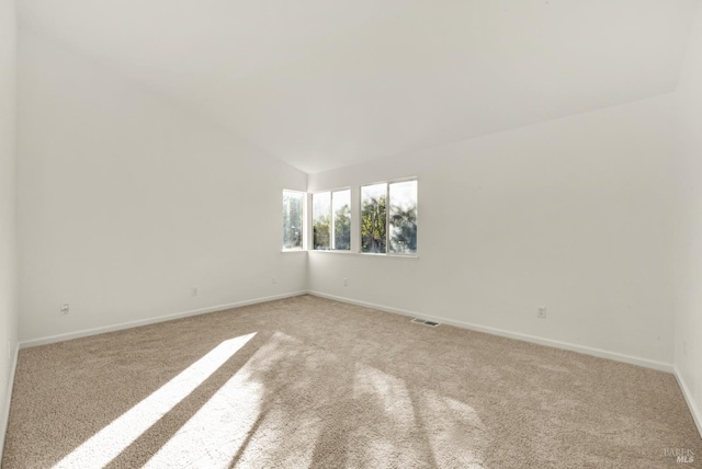 spare room featuring light colored carpet and baseboards