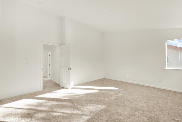 spare room featuring light colored carpet and baseboards