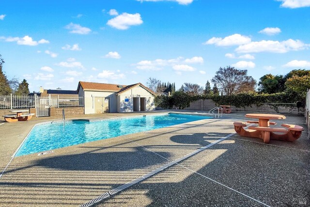community pool with a patio area and fence
