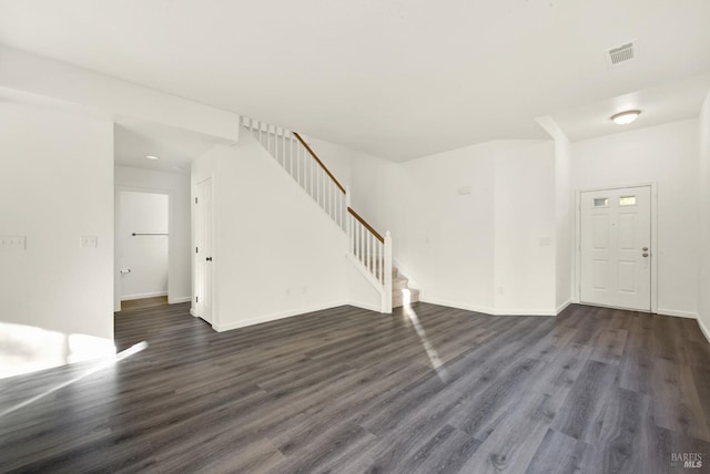 unfurnished living room featuring dark wood-style flooring, visible vents, baseboards, and stairway