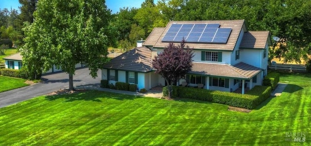 view of front of home featuring solar panels and a front yard