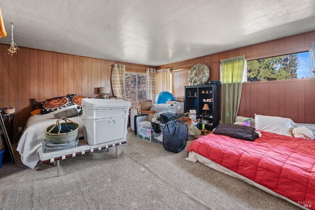 carpeted bedroom featuring wood walls and a textured ceiling