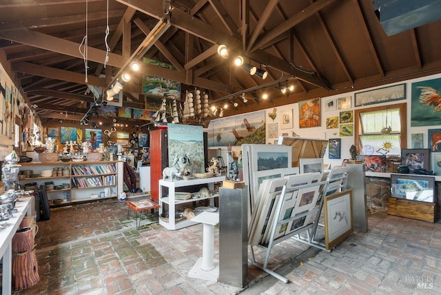 miscellaneous room with rail lighting, beam ceiling, high vaulted ceiling, and a workshop area